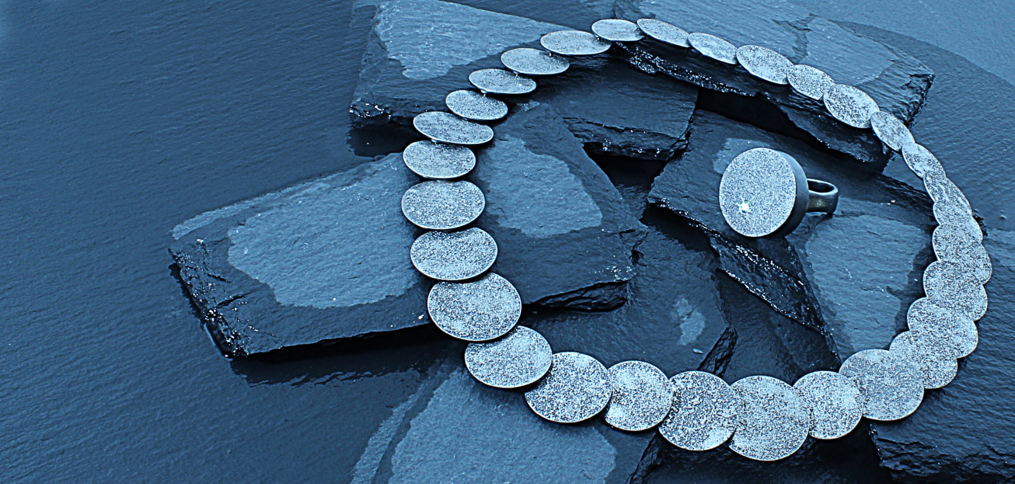 Collier und Ring auf dunklem Untergrund